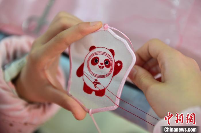 圖為一名小學(xué)生正在繡制2022年北京冬奧會(huì)吉祥物“冰墩墩”形象?！∮髟屏?攝