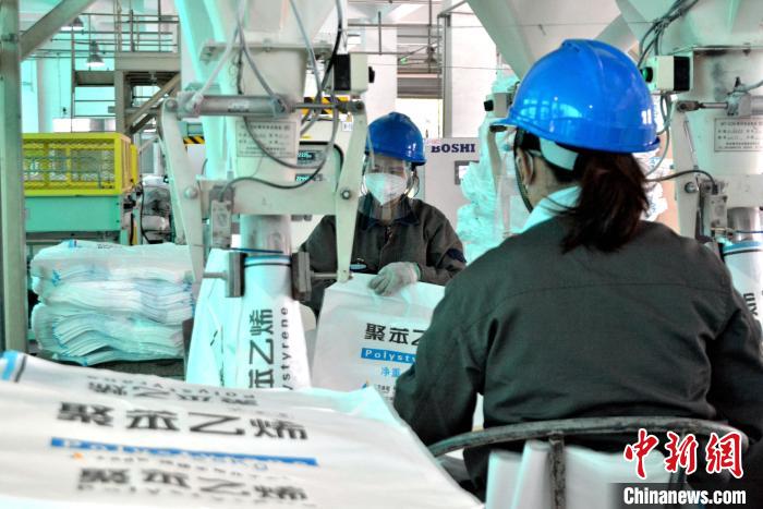 工人在生產(chǎn)線上包裝聚苯乙烯產(chǎn)品?！×趾霔v 攝