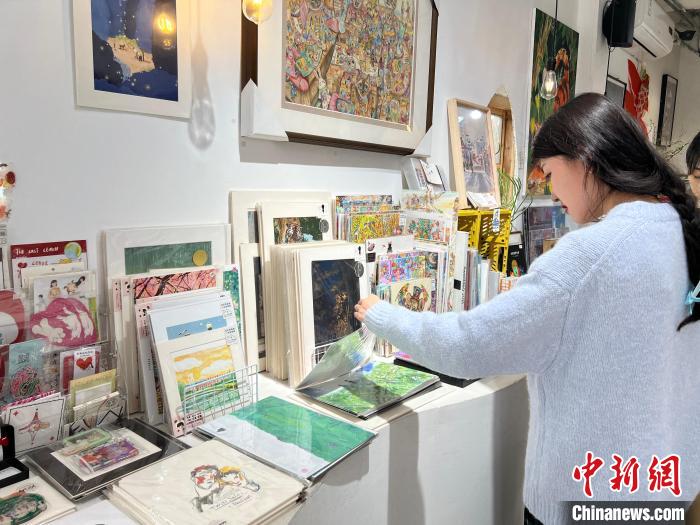 圖為藝術(shù)品商店內(nèi)，顧客挑選插畫作品?！＄婌?攝