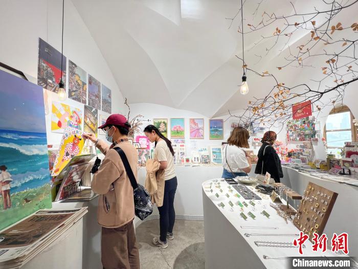 圖為藝術(shù)品商店內(nèi)，顧客挑選插畫作品?！＄婌?攝