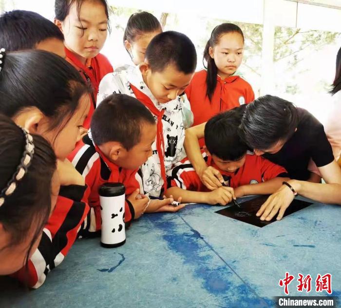 圖為朱增平(右一)教學(xué)生創(chuàng)作鍥金畫。(資料圖) 受訪者供圖