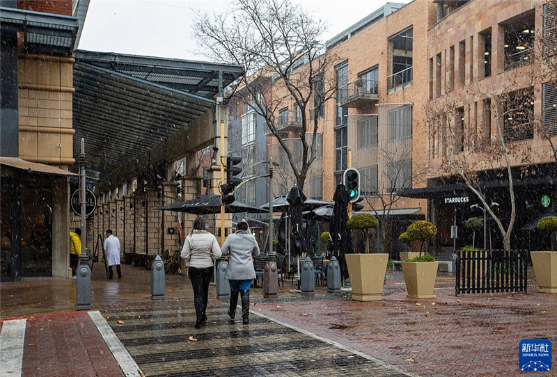 7月10日，在南非約翰內(nèi)斯堡一處商業(yè)區(qū)，人們在雪中行走。新華社記者 張譽東 攝