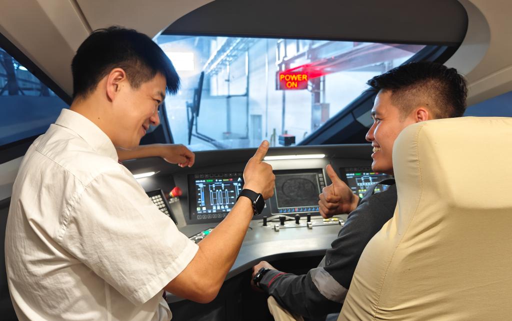 8月25日，在印度尼西亞萬隆的雅萬高鐵德卡魯爾動車所內，中國師傅穆振（左）在向印尼火車司機塞蒂亞萬講解動車組出庫前的上電作業(yè)。