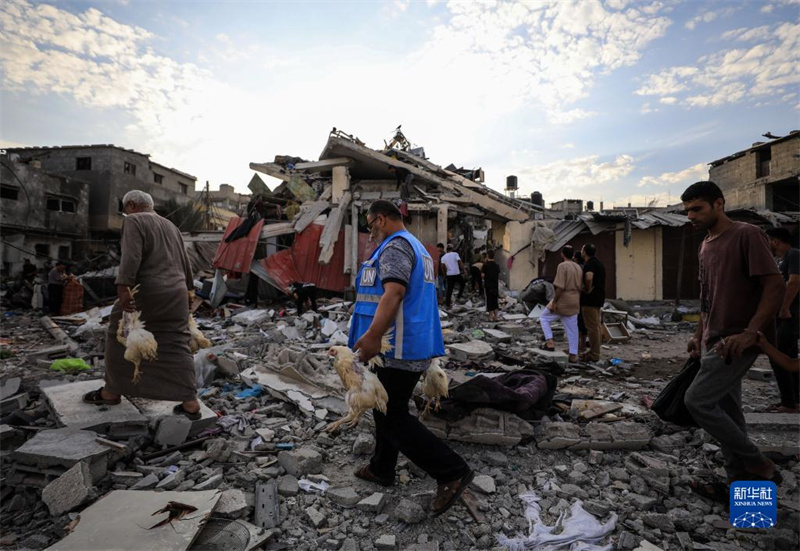 10月27日，在加沙地帶南部城市汗尤尼斯，人們經(jīng)過以軍襲擊后的房屋廢墟。