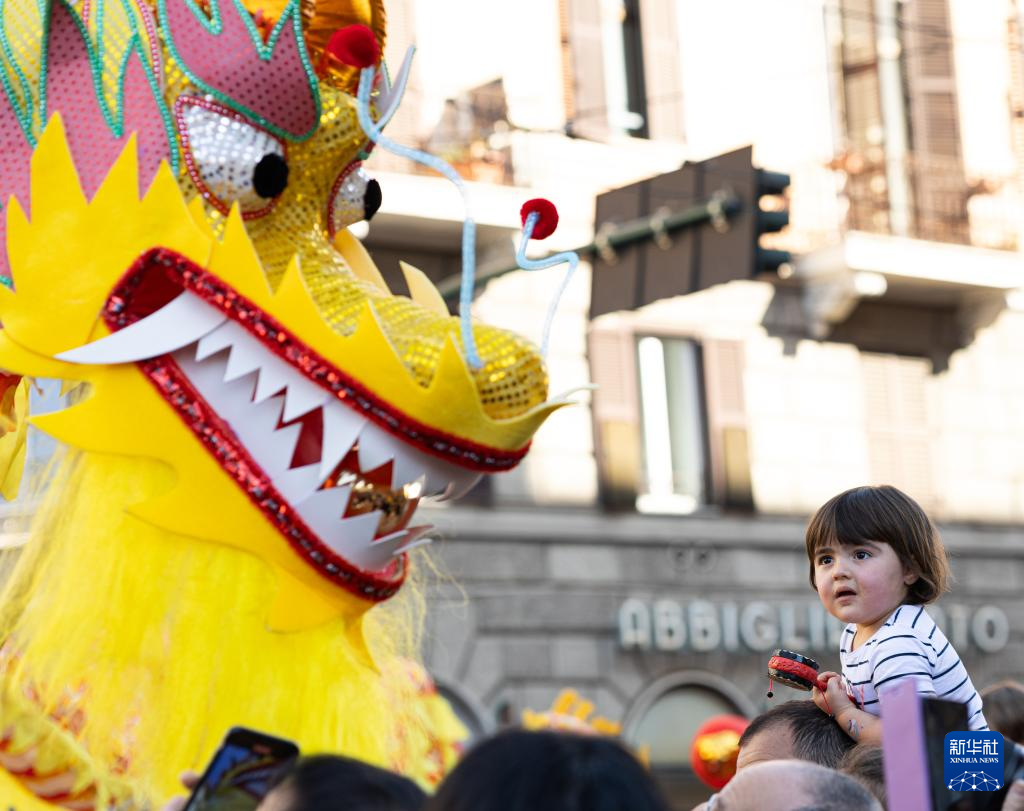 2月18日，在意大利羅馬，一名小朋友在彩妝巡游上觀看舞龍。新華社記者 李京 攝