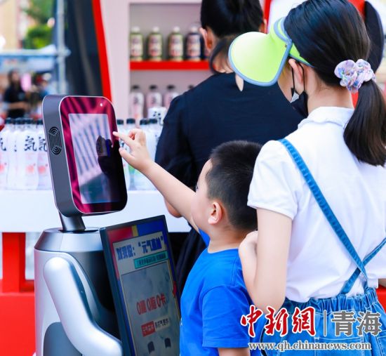 圖為一名小朋友正在和機器人“志愿者”進行互動。 沐聞 攝