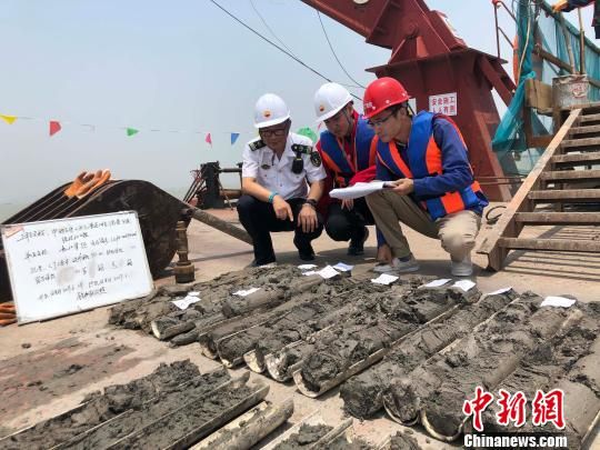 圖為勘察設(shè)計人員與海事局工作人員查看巖芯情況?！∥赫?攝
