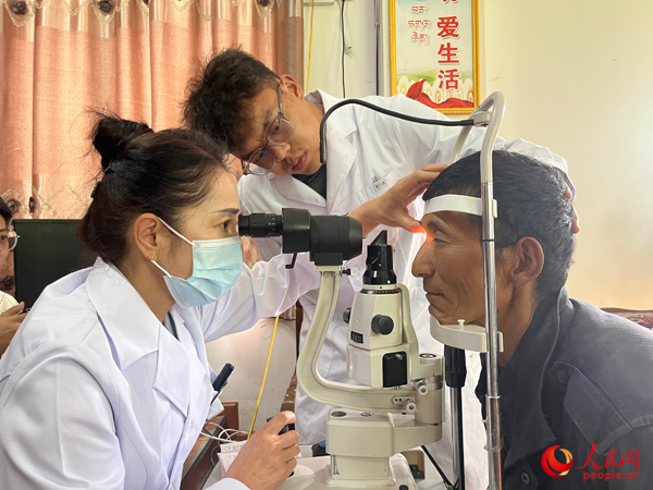 王紅英（左）和團(tuán)隊(duì)成員為達(dá)熱村村民檢查眼睛。人民網(wǎng)記者 杜燕飛攝