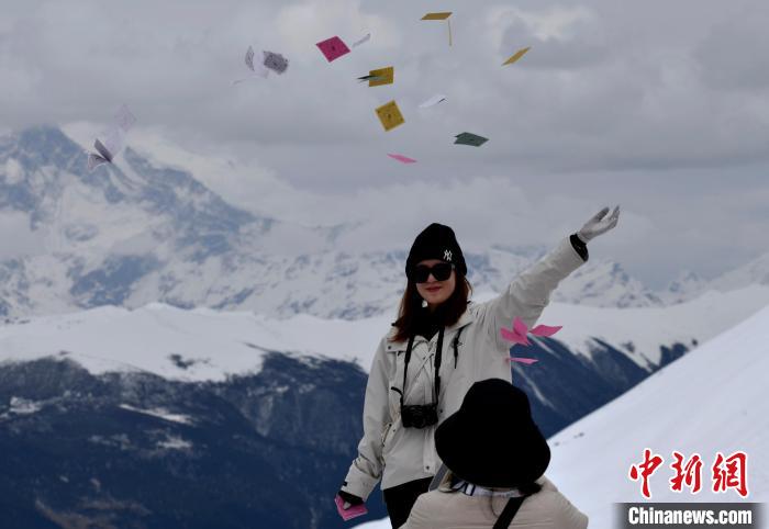 圖為5月14日，游客在西藏林芝色季拉山觀景臺拋灑“隆達”(風(fēng)馬旗，藏族民眾的一種祈福方式)?！±盍?攝