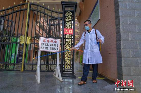 資料圖：?？诮?jīng)濟(jì)學(xué)院的工作人員在學(xué)生宿舍樓入口消毒。 中新社記者 駱云飛 攝