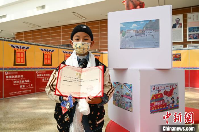 圖為一名獲獎(jiǎng)學(xué)生與自己的繪畫作品合影?！≮w朗 攝