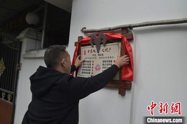 桂溪鎮(zhèn)渭溝村政府工作人員為“十星級文明戶”掛上牌匾。　楊勇 攝