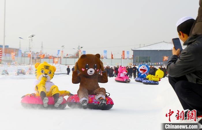 圖為臨夏市南龍鎮(zhèn)馬家莊村舉辦的鄉(xiāng)村文化旅游節(jié)上，游客穿著卡通服裝在體驗(yàn)雪上飛碟項(xiàng)目。近年來，臨夏州形成了“春賞花、夏避暑、秋摘果、冬玩雪”的全季節(jié)旅游產(chǎn)品體系。(資料圖) 高展 攝