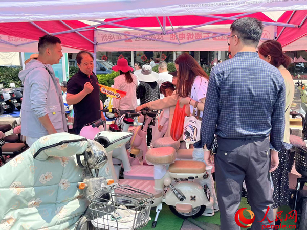 某電動自行車品牌工作人員向消費(fèi)者介紹以舊換新相關(guān)情況。人民網(wǎng)記者 杜燕飛攝