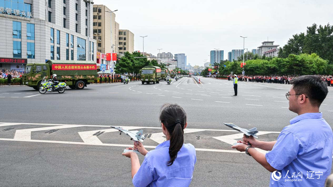 航空工業(yè)沈飛的青年技術(shù)人員拿著受閱戰(zhàn)機(jī)的模型迎接烈士遺骸。航空工業(yè)沈飛供圖