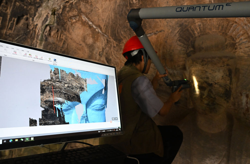 2025年4月9日，武漢大學文化遺產(chǎn)智能計算實驗室團隊成員在魏字洞使用關節(jié)臂掃描儀對佛像進行數(shù)字化掃描。圖片來源新華社