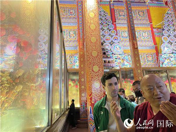 7月25日，省級(jí)非物質(zhì)文化遺產(chǎn)項(xiàng)目塔爾寺酥油花的代表性傳承人朋措堅(jiān)參（右）在塔爾寺酥油花館講解酥油花的制作過(guò)程。人民網(wǎng) 謝瑩攝