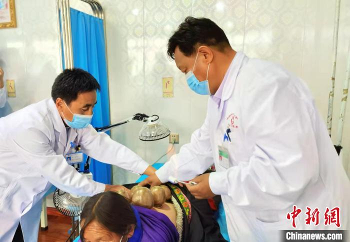 圖為看照加手把手帶徒弟加老(左一)進(jìn)行拔罐療法?！堟?攝