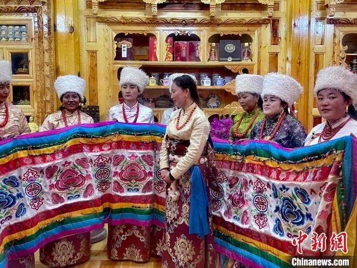 圖為女性展示村民自發(fā)繡制的“百米五彩哈達”?！±钣穹?攝