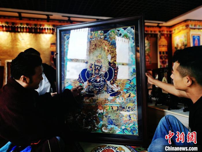 圖為久美尖措(左)與徒弟們展示唐卡作品?！?zhí)砀?攝