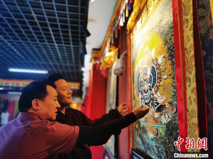 圖為久美尖措展示唐卡作品?！?zhí)砀?攝