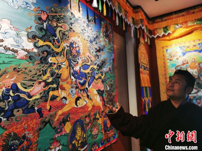 圖為久美尖措展示唐卡作品?！?zhí)砀?攝