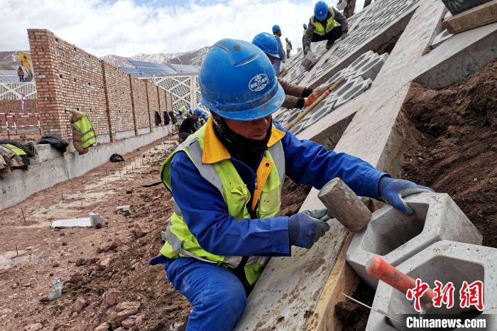 圖為光伏發(fā)電項(xiàng)目施工區(qū)工人在護(hù)坡鋪設(shè)空心磚?！±铍h 攝