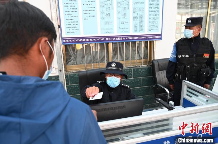 圖為移民管理警察登記完身份信息后將證件歸還給行人?！≮w朗 攝