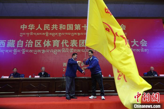 西藏自治區(qū)副主席甲熱·洛桑丹增授代表團團旗，西藏自治區(qū)體育局局長尼瑪次仁接旗?！∪轿木?攝