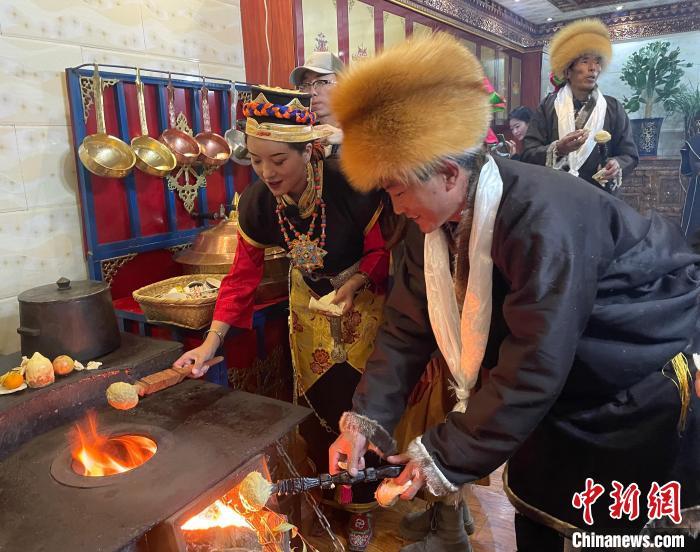 圖為人們在火上烤節(jié)日美食“結達”?！∪轿木?攝