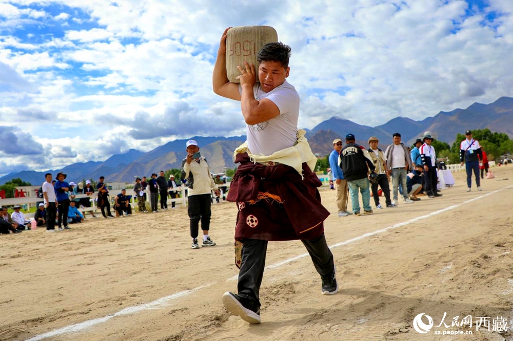 來自拉薩市當(dāng)雄縣的牧民選手將一塊150斤重的石頭扛在肩上飛奔。