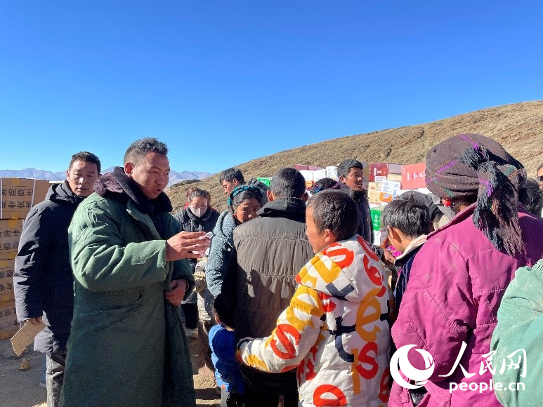 定日縣公安局干警頓珠次仁（左二）正在協(xié)助分發(fā)物資。人民網(wǎng)記者 郝潔攝